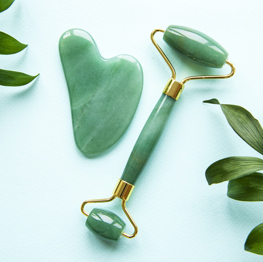 A jade roller placed next to an implement for a Gua Sha treatment.