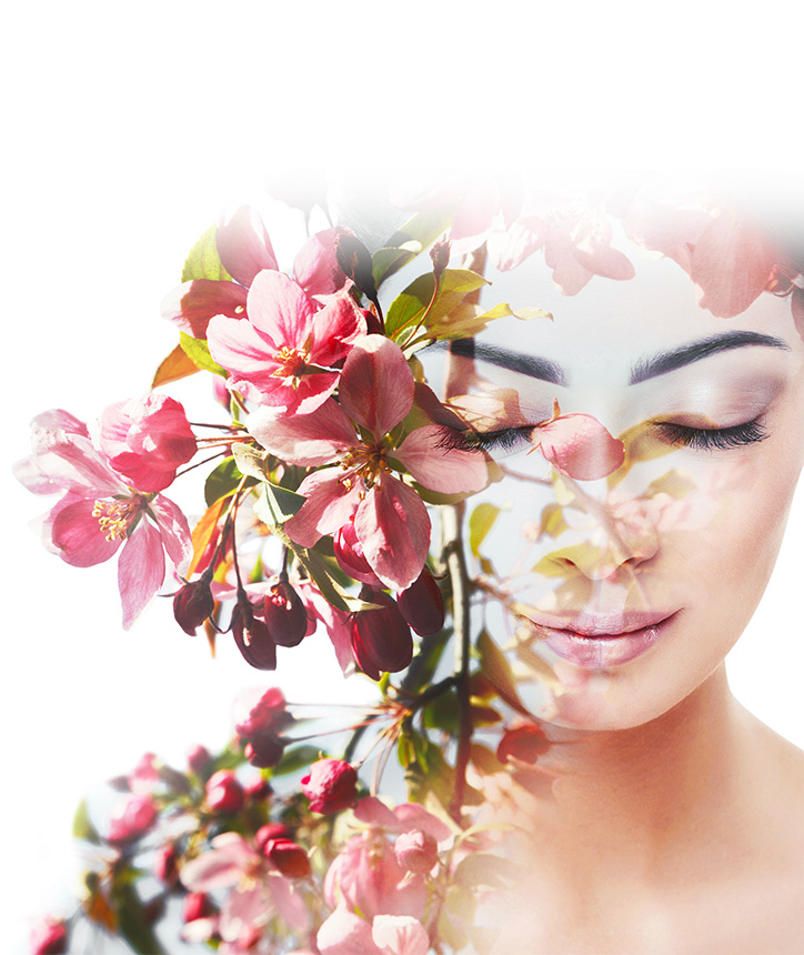 A woman looking downwards, holding a bough of flowers against her face